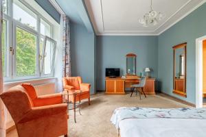 1 Schlafzimmer mit einem Bett, 2 Stühlen und einem Schreibtisch in der Unterkunft Spa & Wellness Hotel Silva in Marienbad
