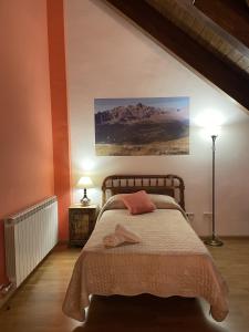 1 dormitorio con 1 cama y una pintura en la pared en Rincón de bachatos en Piedrafita de Jaca