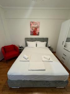 een slaapkamer met een groot wit bed en een rode stoel bij The Nest in Thessaloniki