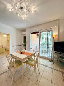 Un comedor con mesa y sillas y un televisor. en Nura's - Casa Flor Seaside, en Alghero