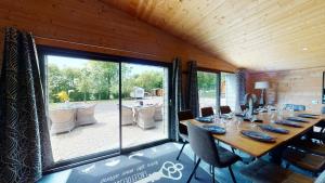 une salle à manger avec une longue table et une grande fenêtre dans l'établissement Cornillières Maisonnettes 35 pers jacuzzi, jeux, à Tessy-sur-Vire 25 autres photos