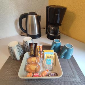 a tray of donuts and coffee cups and a coffee maker at Neoresid - Résidence du Parc in Reims