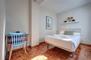 1 dormitorio con cama, escritorio y silla azul en Camino Pamplona 5 by Clabao, en Pamplona