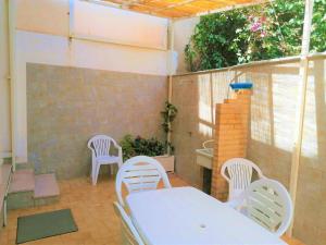 un patio con sillas blancas y una mesa y sillas blancas. en Gambusia appartamenti en Scoglitti