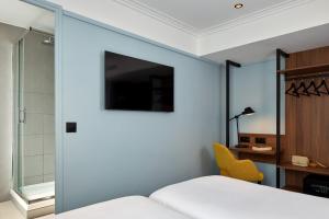 パリにあるティモテル パリ デュ ガール デュ ノールのベッドルーム1室(ガラスの引き戸、ベッド1台、黄色い椅子付)