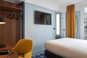 a bedroom with a bed and a desk and a chair at Timhotel Paris du Gare du Nord in Paris