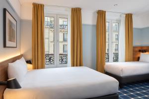 パリにあるティモテル パリ デュ ガール デュ ノールのベッド2台と窓が備わるホテルルームです。