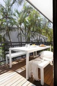 a white table and bench on a balcony with trees at Tingum in Lennox Head