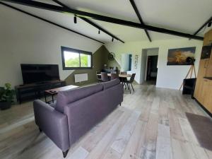 a living room with a purple couch and a table at L'ATELIER 5 couchages avec climatisation in Malville
