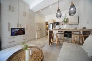 a kitchen and living room with white cabinets and a table at To Stenaki Apartments in Kalymnos
