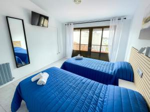 2 camas azules en una habitación con ventana en Hostal Tamanaco Illa de Arousa 3000, en A Illa de Arousa