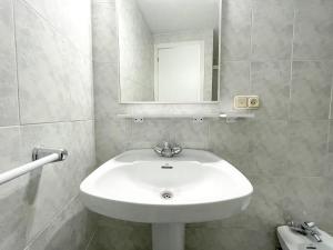 lavabo blanco en el baño con espejo en Hostal Tamanaco Illa de Arousa 3000 en Isla de Arosa