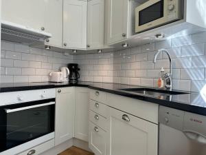 a kitchen with white cabinets and a sink and a microwave at Stay Inn Luxury Apartments Ostermalm in Stockholm +6 photos