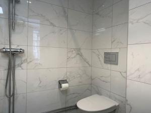 a white bathroom with a toilet and a shower at Stay Inn Luxury Apartments Ostermalm in Stockholm