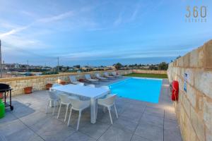 a patio with a table and chairs next to a swimming pool at LUX Villa with Private Pool, BBQ & Rooftop Oasis by 360 Estates in Il-Wileġ