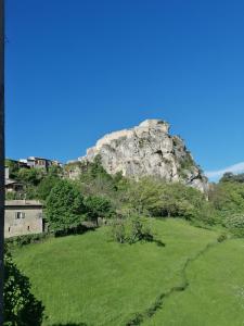 a mountain with a green field in front of it at Au Relais Fleuri in Gilette