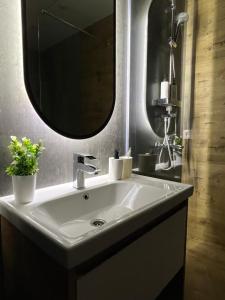 ein Badezimmer mit einem weißen Waschbecken und einem Spiegel in der Unterkunft Апартаменты люкс класса in Pawlodar