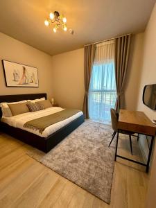 1 dormitorio con cama, escritorio y ventana en F1 Circuit View 1 Bd Apartment en Abu Dabi