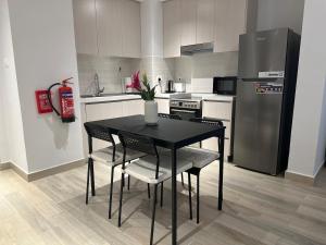 uma cozinha com uma mesa e cadeiras pretas e um frigorífico em Partial Canal View 1br Apartment Yas Island em Abu Dhabi