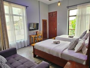 a bedroom with two beds and a couch and a television at Medan Hotel in Ngateu