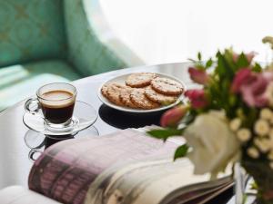 a table with a cup of coffee and a plate of cookies at Le Grand Hotel de Cabourg - MGallery Collection in Cabourg