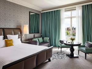 a bedroom with a large bed and a table and chairs at Le Grand Hotel de Cabourg - MGallery Collection in Cabourg
