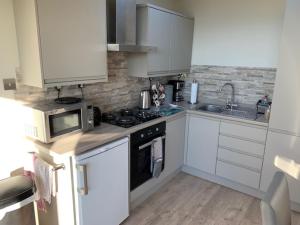 uma cozinha com armários brancos, um fogão e micro-ondas em Sunset Retreat Lodge with Hot Tub em Carsethorn