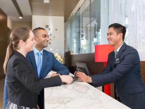 a group of three people shaking hands at a table at Pullman Sydney Olympic Park in Sydney