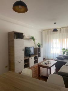 Una sala de estar con un sofá, un televisor y una mesa. en A casa da Tita, en Redondela