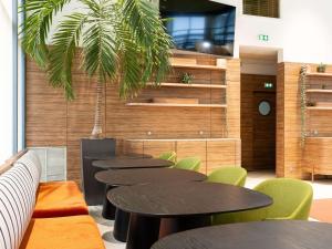 um grupo de mesas e cadeiras numa sala com uma palmeira em Aparthotel Adagio Bordeaux Centre Gambetta em Bordeaux