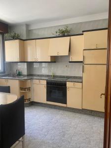 Una cocina con gabinetes de color canela y un lavavajillas negro. en A casa da Tita, en Redondela 12 fotos más