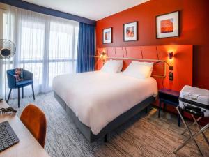 フレジュスにあるMercure Thalasso & Spa Port Fréjusの大きなベッドとデスクが備わるホテルルームです。