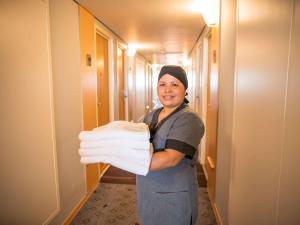 a woman holding a pile of towels in a hallway at ibis Itu Plaza Shopping in Itu
