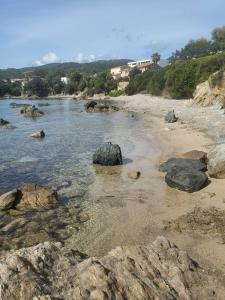 una spiaggia con rocce in acqua di Solenzara charmant appartement vue mer panoramique a Sari Solenzara