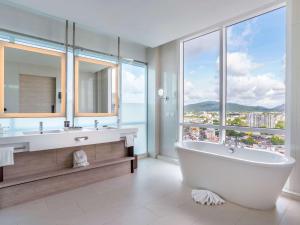 a bathroom with a large tub and a large window at Novotel Phuket City Phokeethra in Phuket