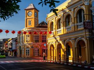 Novotel Phuket City Phokeethra في فوكيت تاون: مبنى اصفر مع برج ساعه على شارع