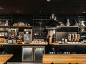 a person standing behind a counter in a restaurant at Ibis Styles Clermont-Ferrand République in Clermont-Ferrand