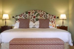 a large bed with a large headboard and two lamps at Capannelle Wine Resort in Gaiole in Chianti