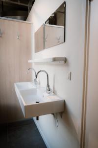 ein Badezimmer mit einem weißen Waschbecken und einem Spiegel in der Unterkunft Stadsklooster Dordt Hotel&Hostel in Dordrecht
