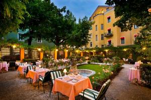 Parkhotel Graz - Traditional Luxury في غراتس: حديقة بها طاولات وكراسي ومبنى