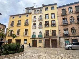 a yellow building with people walking in front of it at Plaza Mercadal, Tudela in Tudela