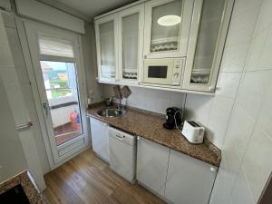 una pequeña cocina con armarios blancos y fregadero en Duplex con Terraza en Mogro, en Mogro