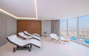 Andaz by Hyatt – Palm Jumeirah في دبي: غرفة انتظار مستشفى مع كراسي بيضاء ونوافذ