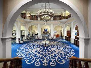 een grote lobby met een kroonluchter en blauw tapijt bij Fairmont Château Lake Louise in Lake Louise