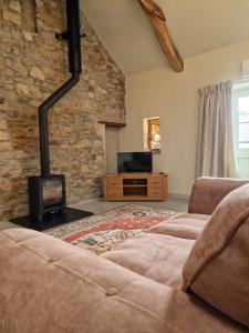 a living room with a couch and a fireplace at Broomhill Barns in Minwear