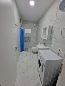 y baño blanco con lavadora. en Anchor Apartments en Shëngjin