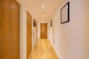 un corridoio con pareti bianche e pavimento in legno di The Greenwich Collection a Londra