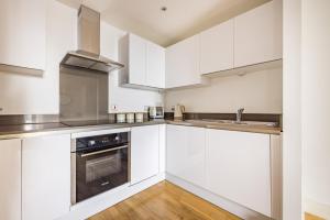 una cucina bianca con elettrodomestici in acciaio inossidabile e pavimenti in legno di The Greenwich Collection a Londra