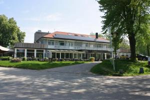 un grand bâtiment blanc avec un arbre en face dans l'établissement Hotel Oranjeoord, à Apeldoorn
