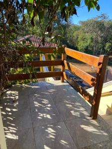 een houten bank op een stoep naast een hek bij Pousada Morro do Frota in Pirenópolis